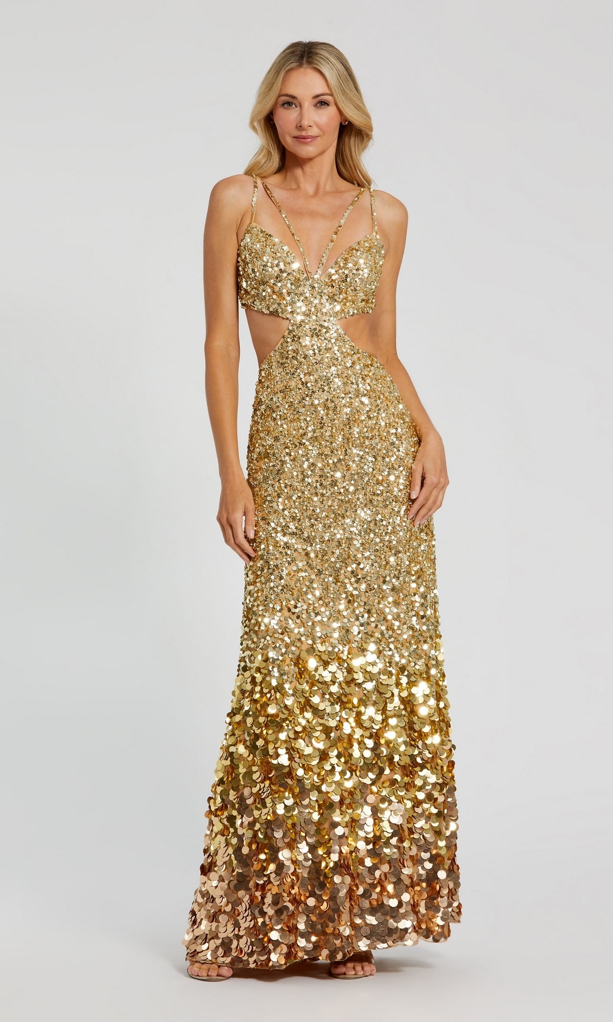 A woman stands against a plain background wearing the Long Formal Dress 6077 by Mac Duggal, featuring floor-length sequins, thin straps, cut out sides, and an open back.